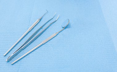 Açık mavi arkaplan ve metin için alanı olan farklı dişçi araçları.