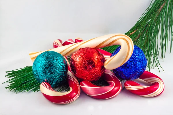 Four candy cans and three chocolate balls on pine twig on a whit — Stock Photo, Image