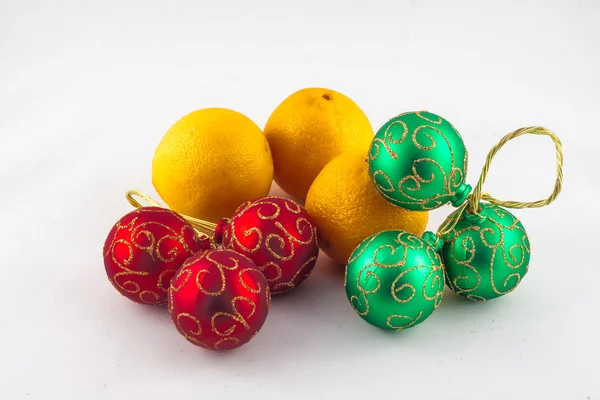 Enfeites de Natal e três mandarinas em um fundo branco — Fotografia de Stock