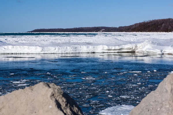 View from the rocky shore of an ice filled lake — Stock Photo, Image