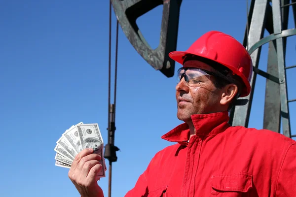 Ölarbeiter mit schmutzigem Gesicht, der uns Dollarscheine hält — Stockfoto