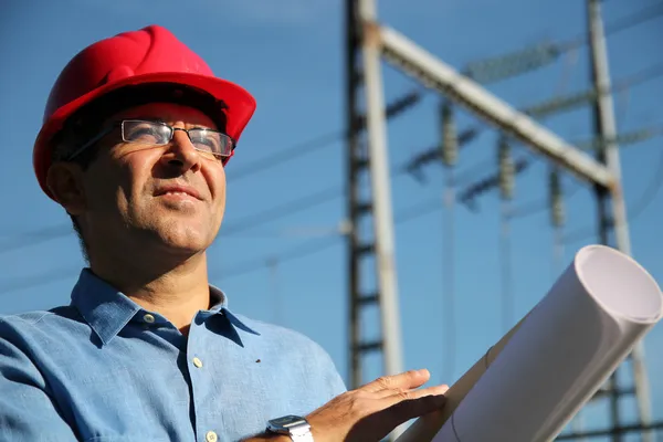 Ingenieur met rode harde hoed en blauwdruk onder de elektrische leidingen. — Stockfoto