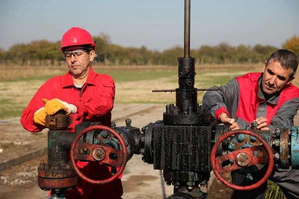 Twee geschoolde olie- en gasindustrie ingenieurs in actie op oliebron. — Stockfoto