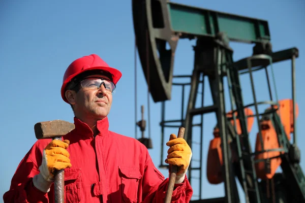 펌프 잭 옆에 있는 석유 산업 노동자 지주 쇠 망치. 로열티 프리 스톡 사진