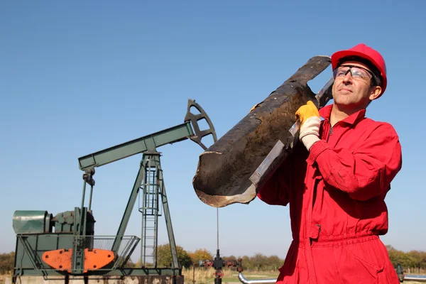 Het olieveld werknemer op goed pomp jack site. — Stockfoto