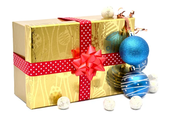 Χρυσή δώρο κουτί με κόκκινη κορδέλα και χριστουγεννιάτικα μπάλες — Φωτογραφία Αρχείου