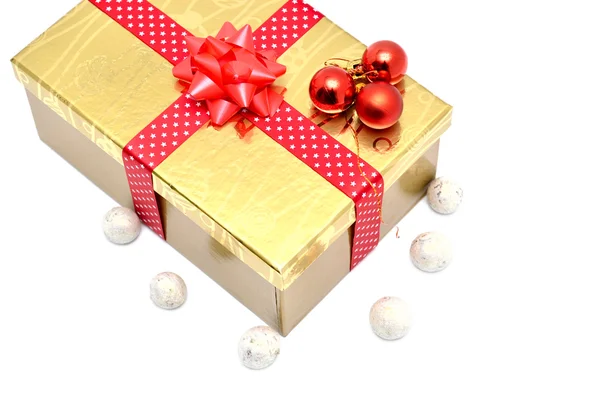 Золота подарункова коробка з червоною стрічкою та червоними різдвяними кульками — стокове фото
