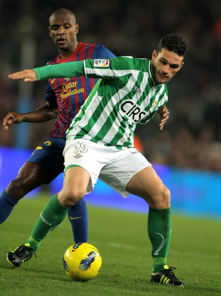 Jorge Molina(R) of Real Betis vies with Eric Abidal(L) of FC Barcelona