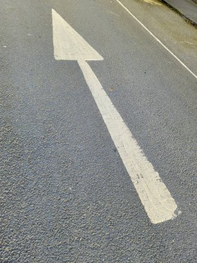 Asfalta ok çizilmiş. Gerekli yön hareketini gösterir. Kaldırımda beyaz yol işaretleri.
