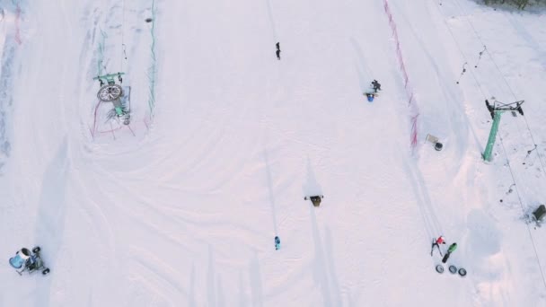 Οι σκιέρ και snowboarders βόλτα στις πίστες χιόνι με αναβατήρες σκι. — Αρχείο Βίντεο