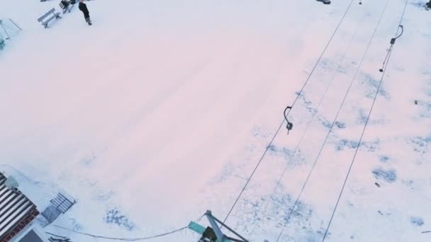 Skiers and snowboarders skiing on snow slopes with ski lift near ski lift wheel. — Stockvideo