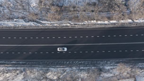 Witte auto en verschillende voertuigen in het wegverkeer langs zwarte asfalt snelweg: top view drone shot. — Stockvideo