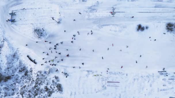 Muchos snowboarders esquiando en la pista de nieve con telesilla en fin de semana - vista superior tiro con dron. — Vídeo de stock