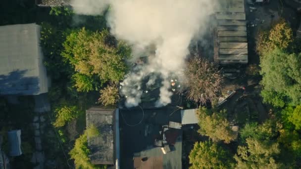 Equipe de resgate com caminhão de bombeiros e bombeiros trabalha para apagar um incêndio na cidade: tiro drone. — Vídeo de Stock
