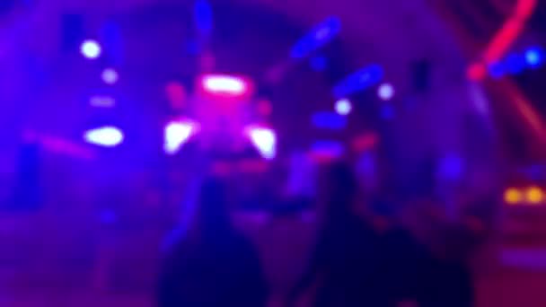 Siluetas de tres chicas bailando cerca de un escenario en un club nocturno: fondo borroso. — Vídeos de Stock
