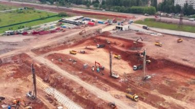 İnşaat kazı çalışmaları inşaat alanında yapılıyor: kamyonlar ve sondaj platformları.