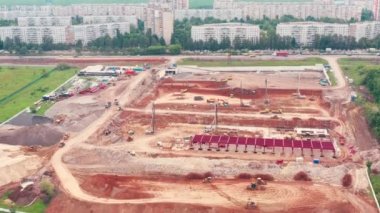 İnşaat malzemeleri inşaat sahasında çalışıyor: Kazıcılar, kamyonlar ve buldozerler - havadan çekim