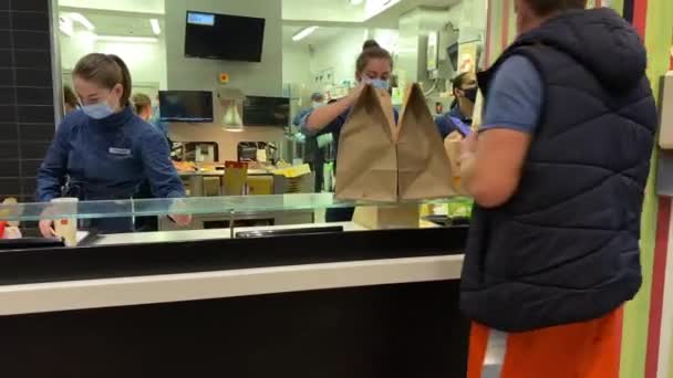 Trabajador de McDonalds en ropa azul empaca el pedido con varios paquetes — Vídeo de stock