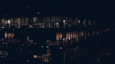 Ofislerdeki insanlarla birlikte bina: Geceleri modern iş binasının ofislerinde çalışan insanlar