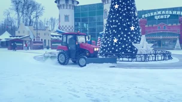 Snowplow Tractor works on snow removal in the park during snowfall during Christmas season — Stock Video