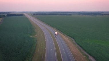 Yarı römorklu beyaz kamyonet köy yolunda ilerliyor.
