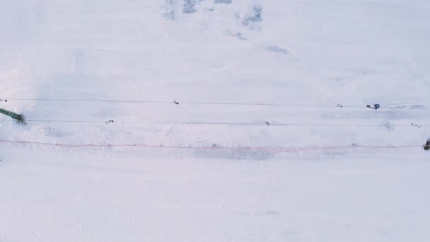 スキーリフトエレベーターの空中トップビュー。スキー場の雪の斜面にスキーやスノーボーダーが登る. — ストック動画