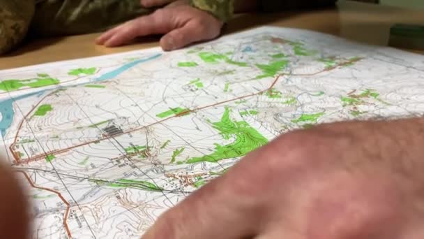Důstojník ukazuje důležité objekty na mapě rukou s hodinkami — Stock video