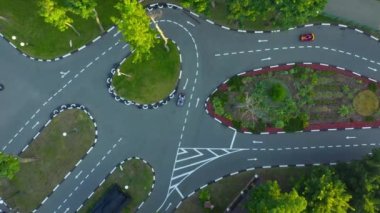 Karting Attraction Track: İnsanlar asfalt yarış pistinde küçük arabalara biniyor: havadan görüntülü insansız hava aracı. Beyaz işaretli asfalt yolda karting hareketi.