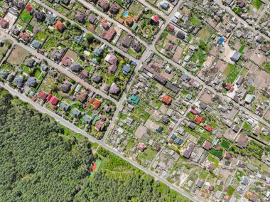 Şehrin yakınında kiremit çatılı evler. Ormanın yakınındaki banliyöde. Düşük yoğunluklu yerleşim bölgelerindeki kulübeler - havadan drone çatısı görüntüsü.