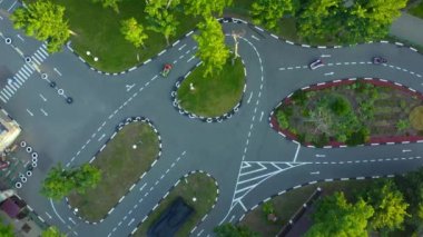 Cazibe Track: İnsanlar asfalt yarış pistinde küçük arabalara biniyorlar: hava manzaralı drone çekimi. Lunapark: parktaki küçük arabalar için bir yarış pisti - hava manzaralı insansız hava aracı görüntüsü.