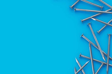 Mavi arka planda dağılmış metal çiviler. İnşaat malzemeleri. Tamir ve yenileme aletleri. Üst Manzara. Uzayı kopyala 3d hazırlayıcı