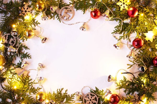 Noel ya da Yeni Yıl arkaplanı: Ahşap oyuncaklar ve parlak bir çelenk, çanlar, toplar ile beyaz arka planda köknar dalları. Tebrik için beyaz çerçeve