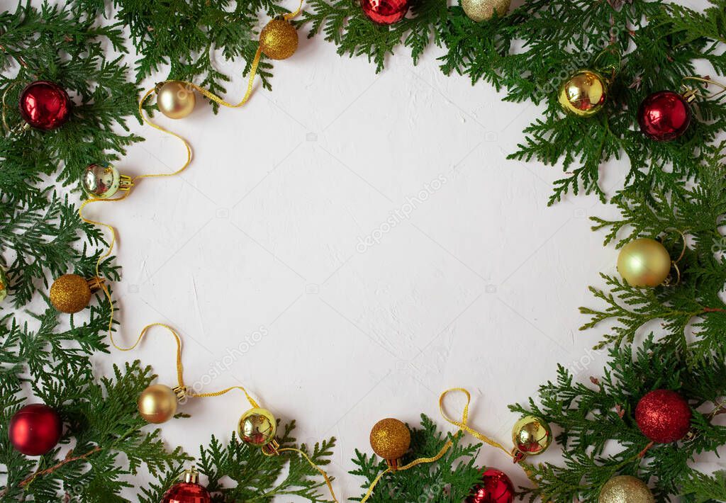 Christmas or New Year background: fir branches on a white background with Christmas balls. White frame for congratulations