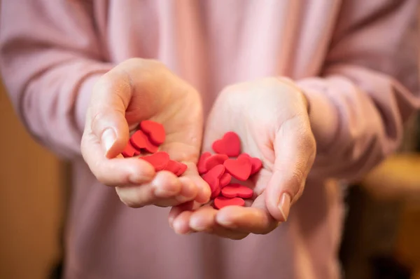 Sevgililer Günü 'nde kırmızı sevgililer günü kartı tutan eller. Kızın elleri bir sürü küçük kalbi ve hızlı yerleştiren plastikleri tutuyor. 14 Şubat 'ta. Aşk tatili. Sevgi verme kavramı