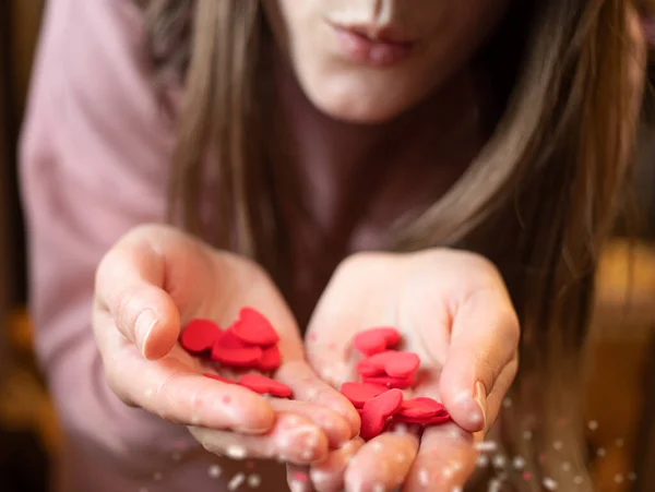 Sevgililer Günü 'nde kırmızı sevgililer günü kartı tutan eller. Kızın elleri bir sürü küçük kalbi ve hızlı yerleştiren plastikleri tutuyor. 14 Şubat 'ta. Aşk tatili. Sevgi verme kavramı