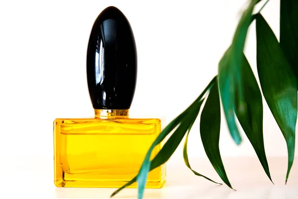 Butelka Przyjemnym Zapachu Perfum Jasnym Tle Żółta Butelka Kwiaty Zielone — Zdjęcie stockowe
