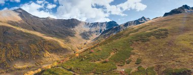 Uçsuz bucaksız dağ sırtı manzarası kayalık tepeler, sonbahar manzarası sarı karışık orman ve yeşil çam ağaçları, sonbaharın sonlarında Chistaya nehir vadisi, zirvelerde taze kar.