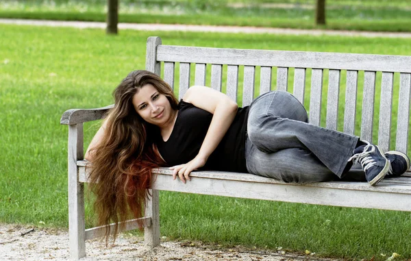 Симпатичная молодая девушка на скамейке — стоковое фото