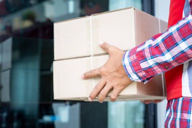 Teslimatçı müşteriye paket kutusu gönderiyor, kırmızı tişört giyen biri de memnun bir müşteriye paket teslim ediyor. Dost canlısı işçi, yüksek kaliteli teslimat servisi..