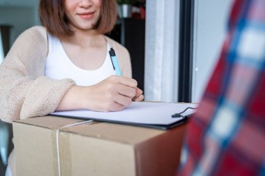 Kuryeden paket alırken kadın belgeleri imzalıyor. Çevrimiçi alışveriş konsepti.