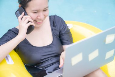 Tatilde çalışan serbest çalışan kadınlar havuzda lastik halkanın üzerinde otururken dizüstü bilgisayarda yazan genç bir kadın. Her yerden çalış, serbest çalış..