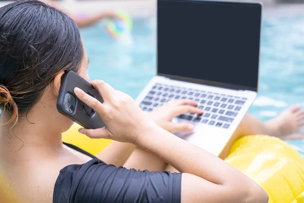 Freelancer women working on vacation, Young woman typing on computer laptop while sitting on rubber ring in the pool. Work from anywhere, freelance.