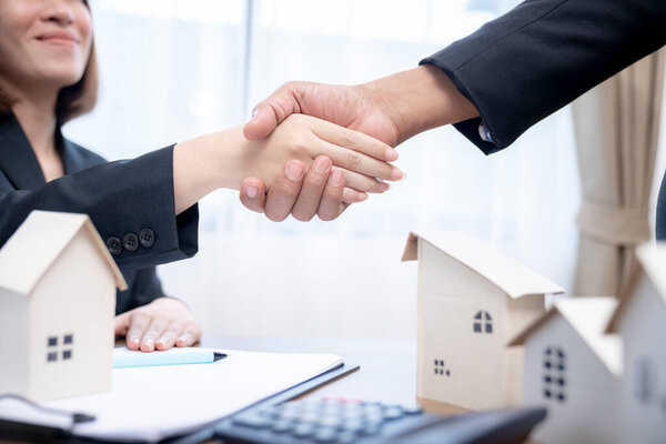 Sealing a deal concept, Estate agent shaking hands with his customer after contract signature.