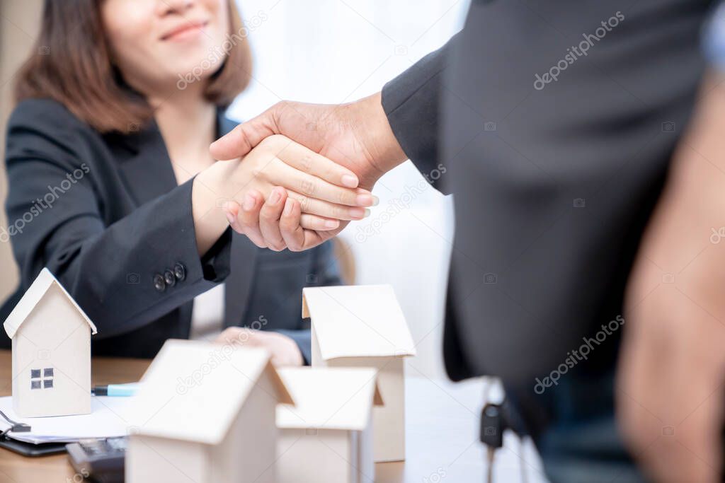 Sealing a deal concept, Estate agent shaking hands with his customer after contract signature.