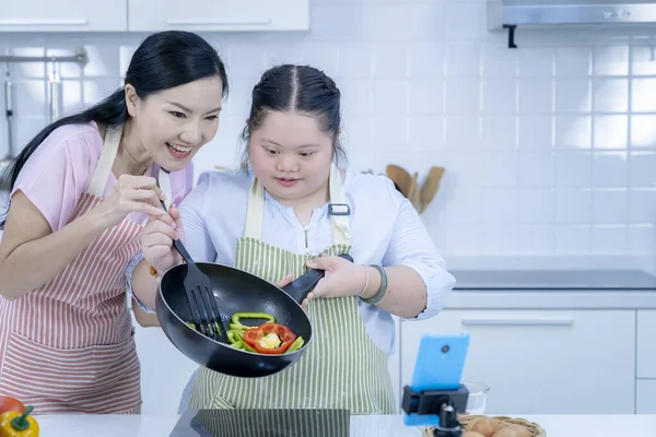 Asian person with Down syndrome cooking with mom. Brain growth learning family love intelligence cooking