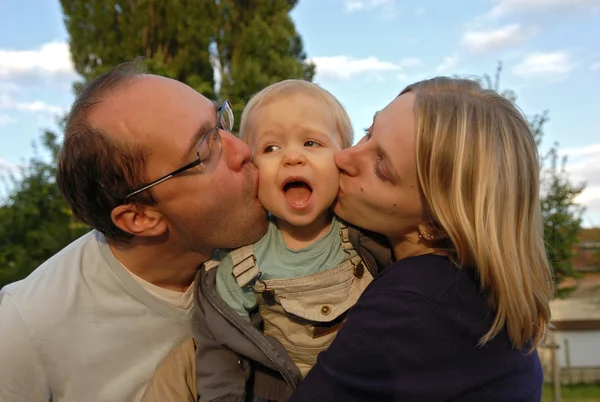 Eltern küssen Kind — Stockfoto