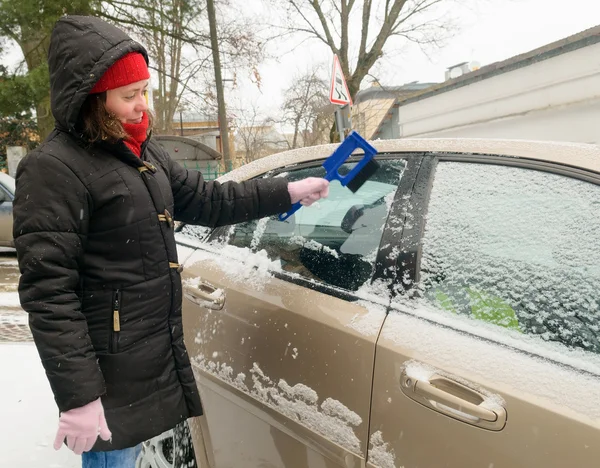 Vrouw reinigt sneeuw auto voorruit — Stockfoto
