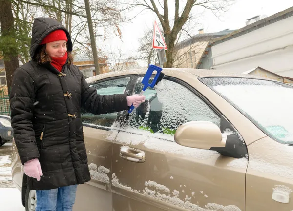 Žena čistí sněhu auto sklo — Stock fotografie