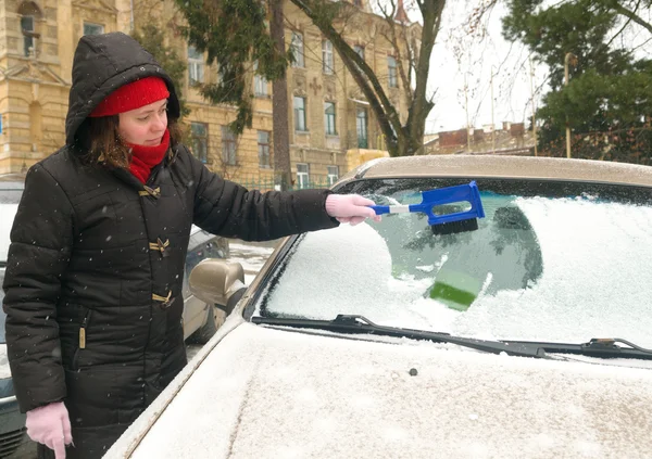Žena čistí sněhu auto sklo — Stock fotografie