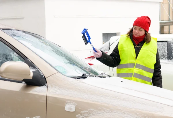 Vrouw reinigt sneeuw auto voorruit — Stockfoto